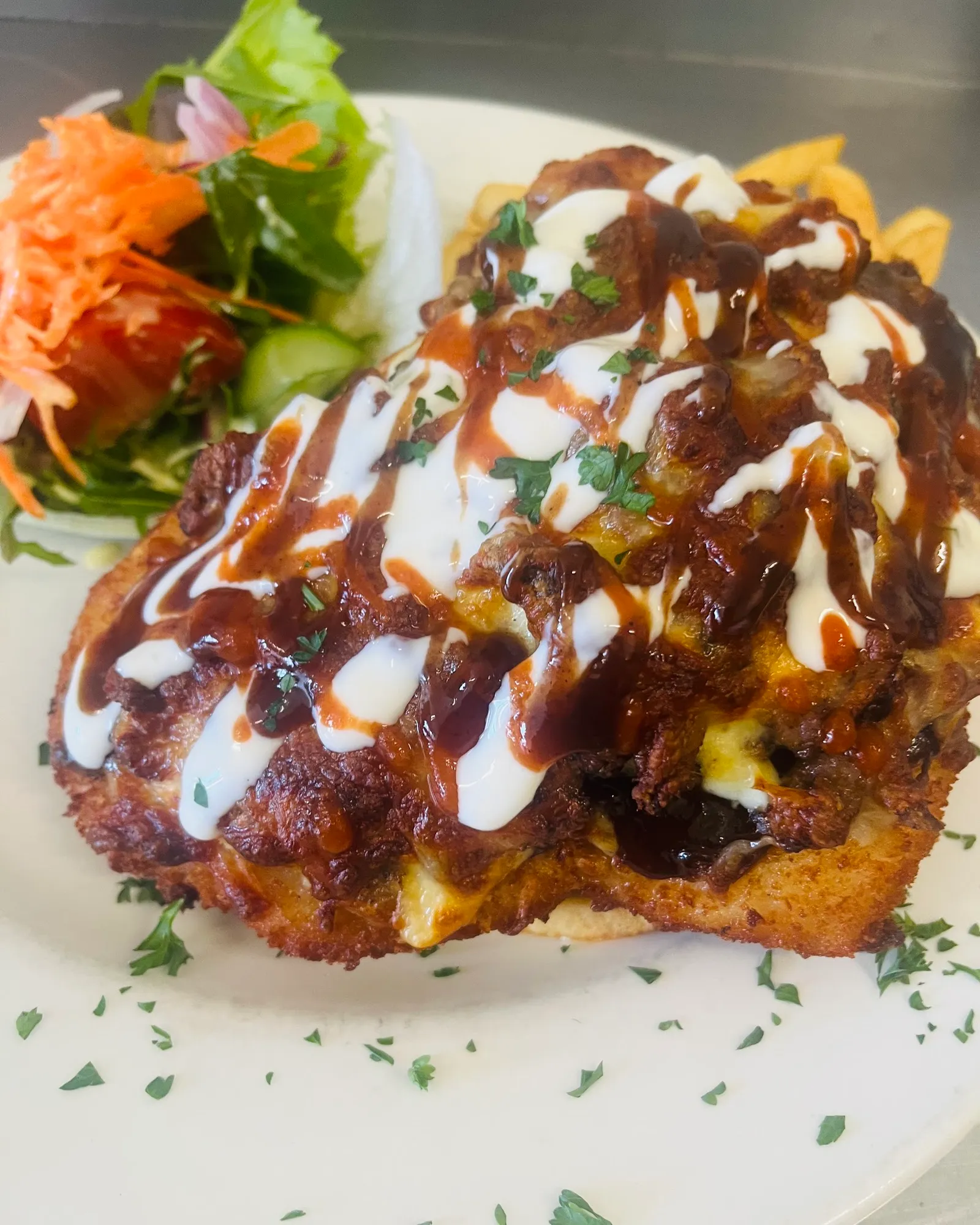 Chicken parmigiana drizzled with aioli, BBQ and chilli sauces