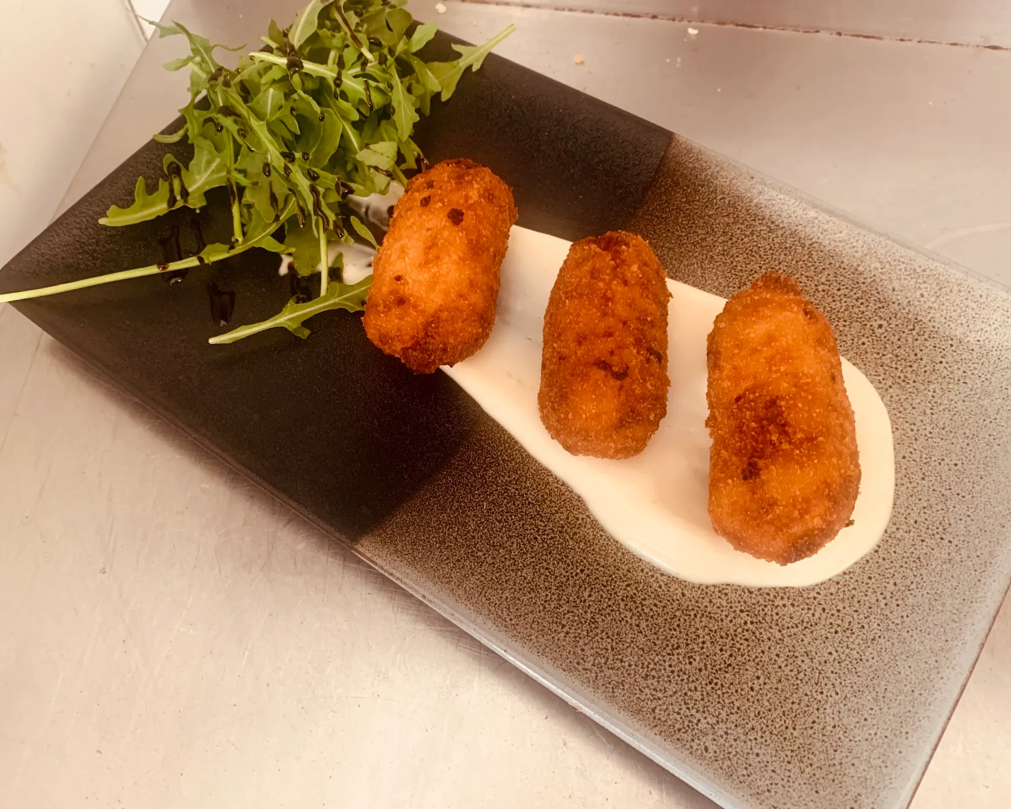 Crumbed croquettes with rocket salad and balsamic drizzle