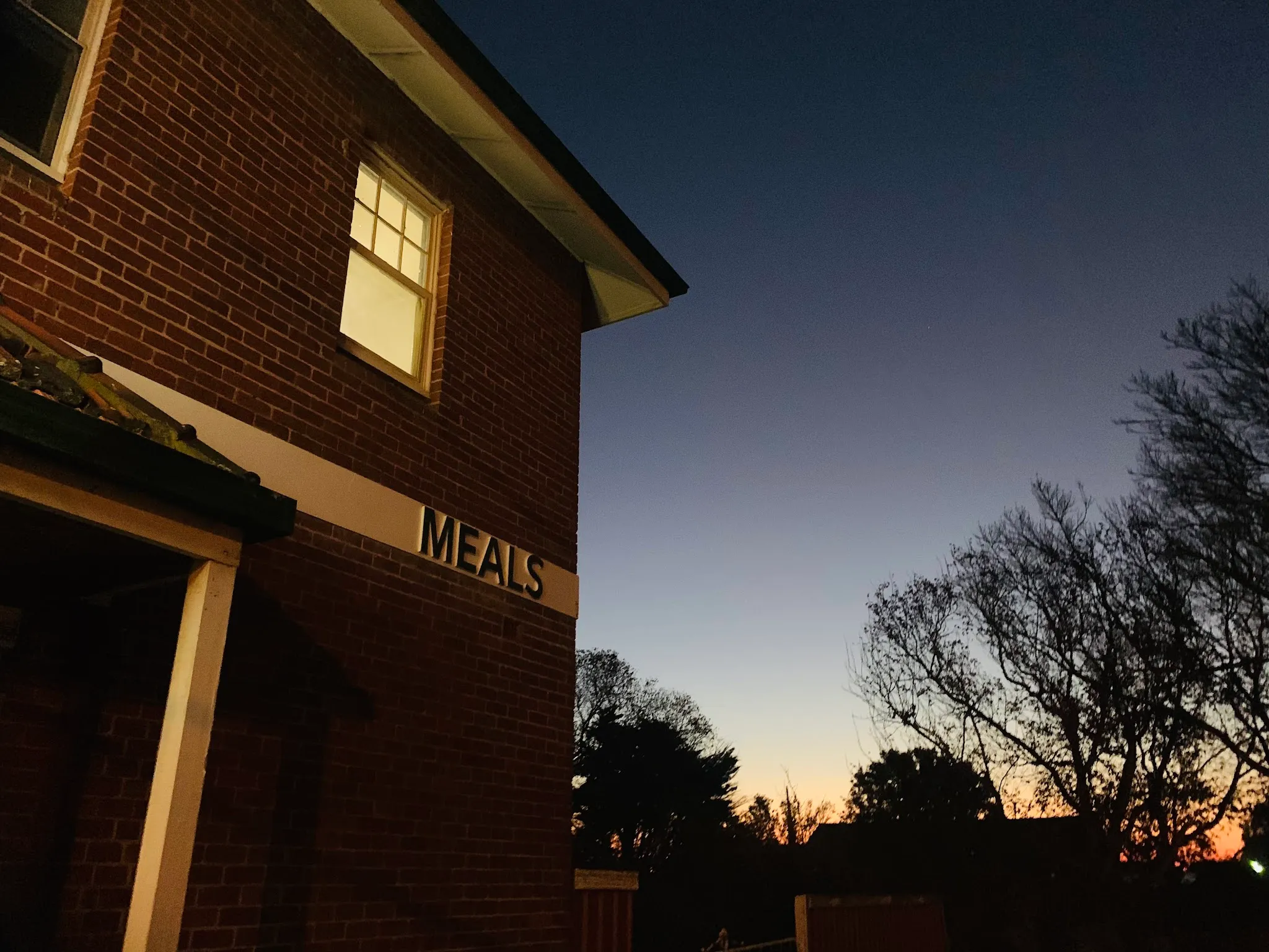 Palace Hotel building corner at dusk with MEALS sign
