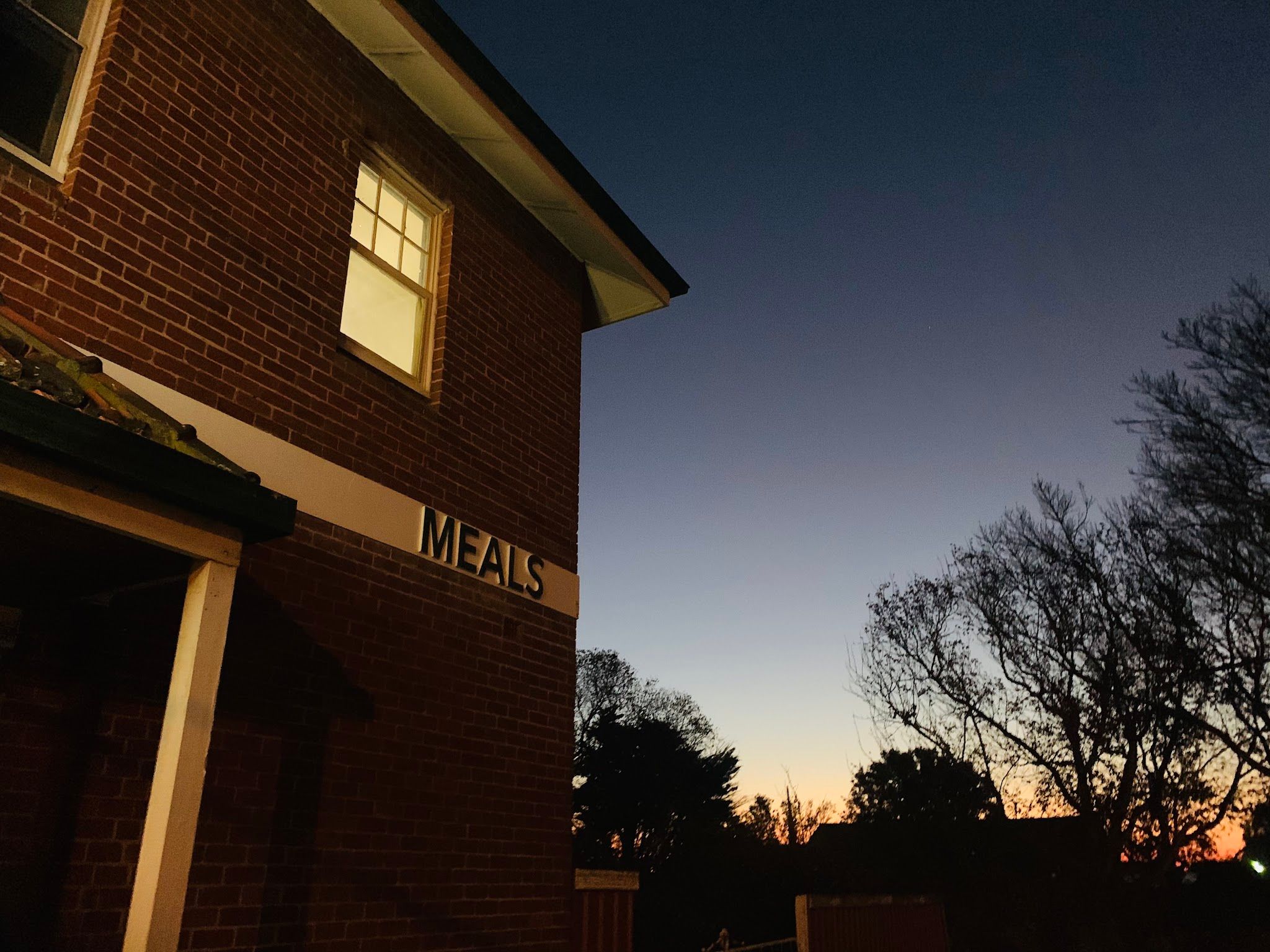 Palace Hotel building corner at dusk with MEALS sign